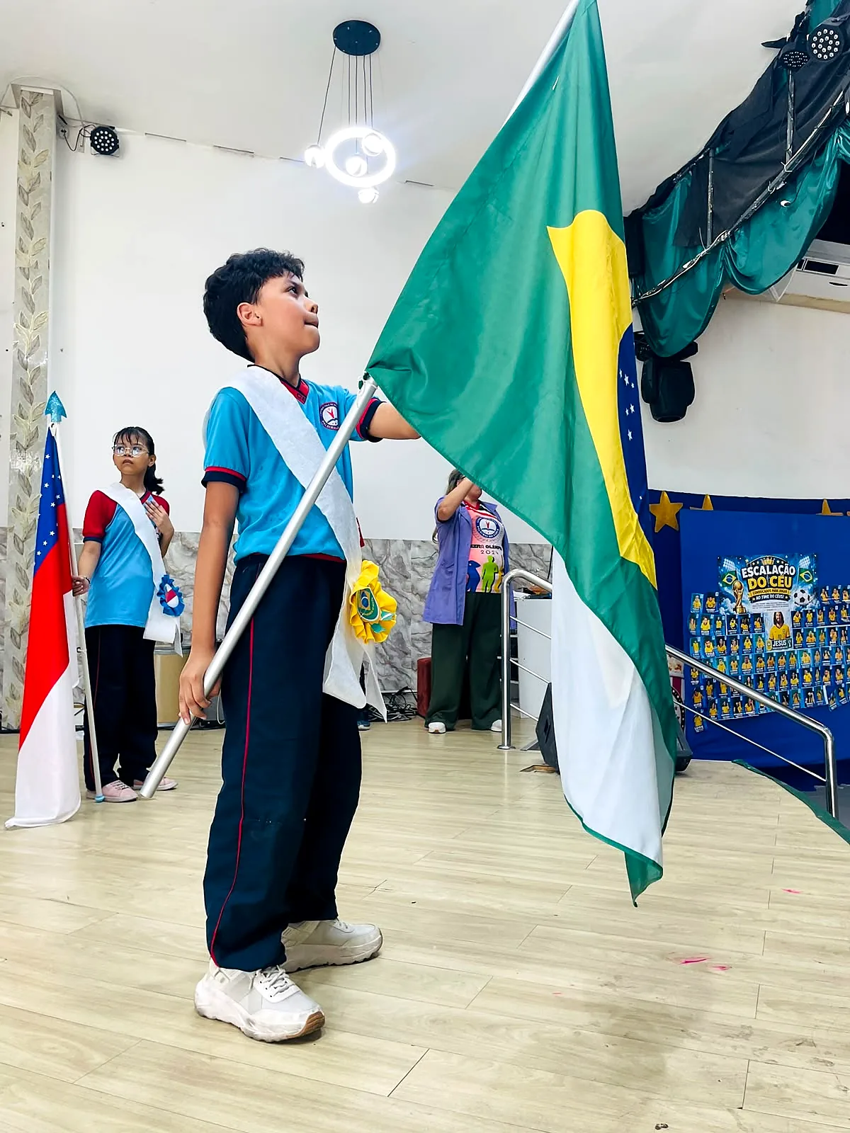 Aluno segurando a bandeira do Brasil na cerimônia de 7 de Setembro da escola